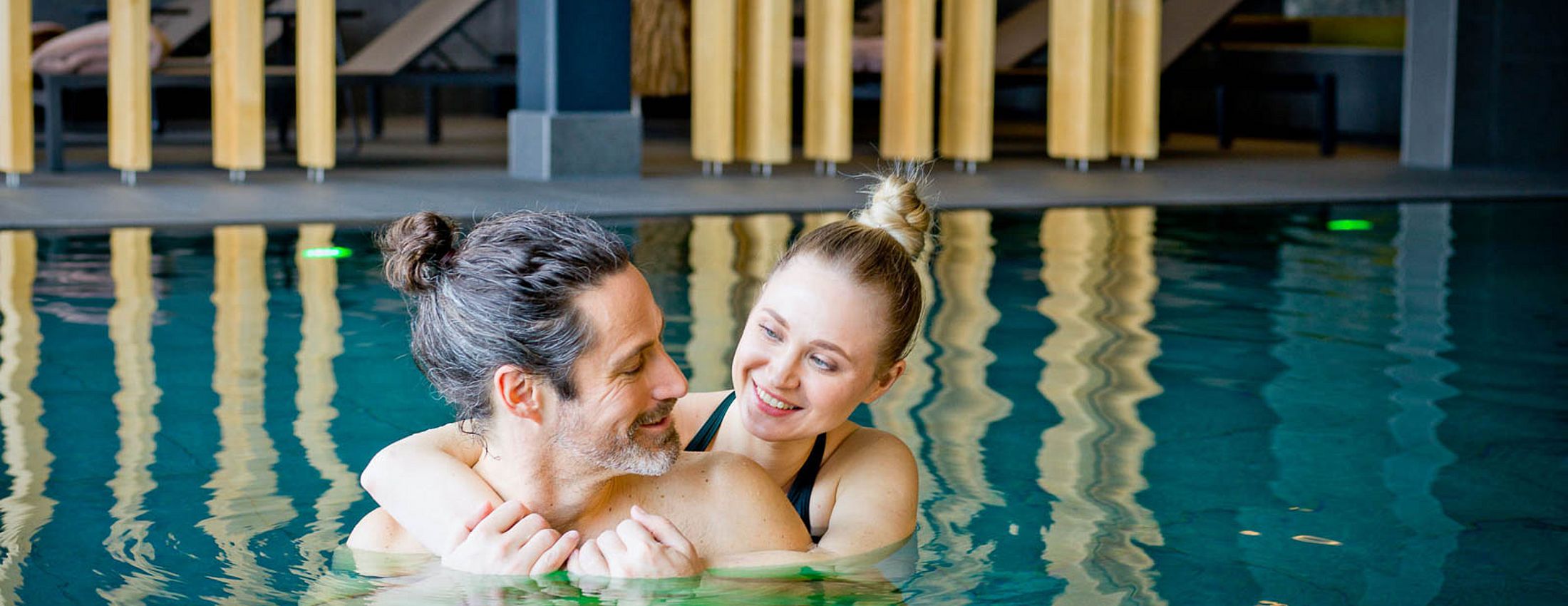 Paar umarmt sich entspannt im Innenpool des Wellnessbereichs