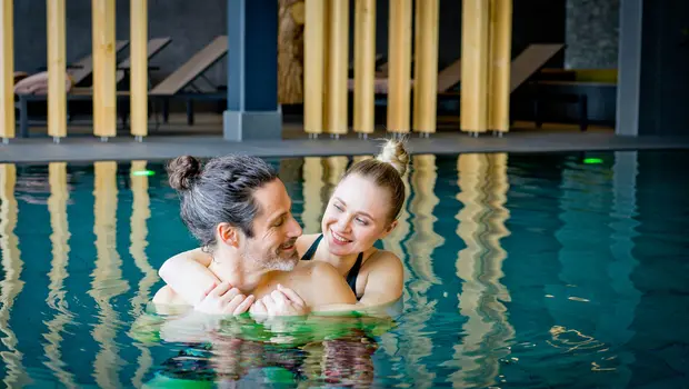 Paar umarmt sich entspannt im Innenpool des Wellnessbereichs
