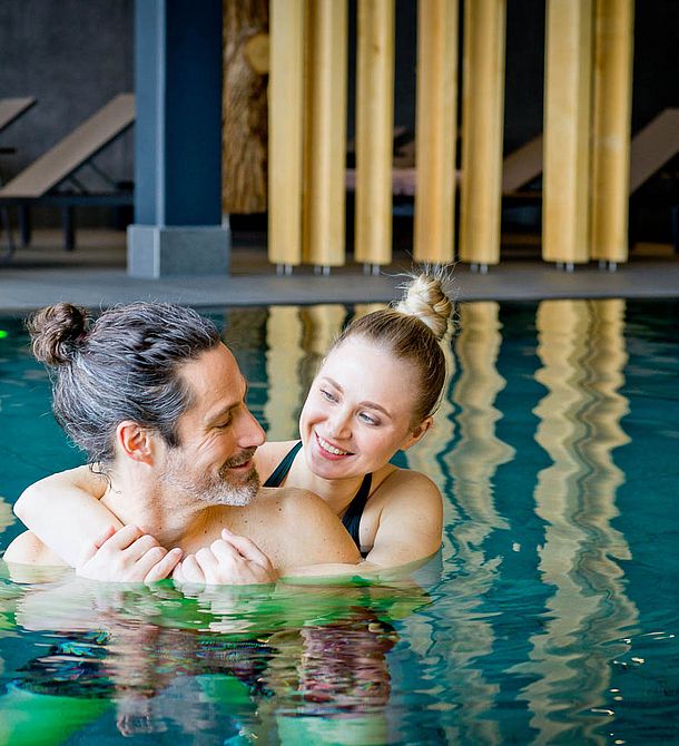 Paar umarmt sich entspannt im Innenpool des Wellnessbereichs