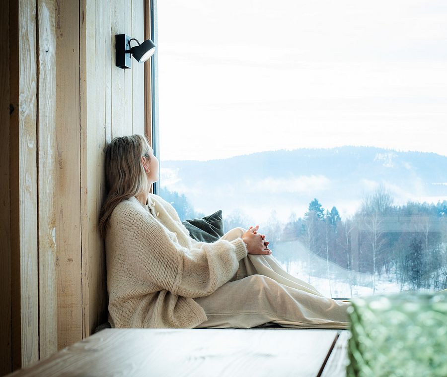 Relaxing at window seat with view of snowy landscape