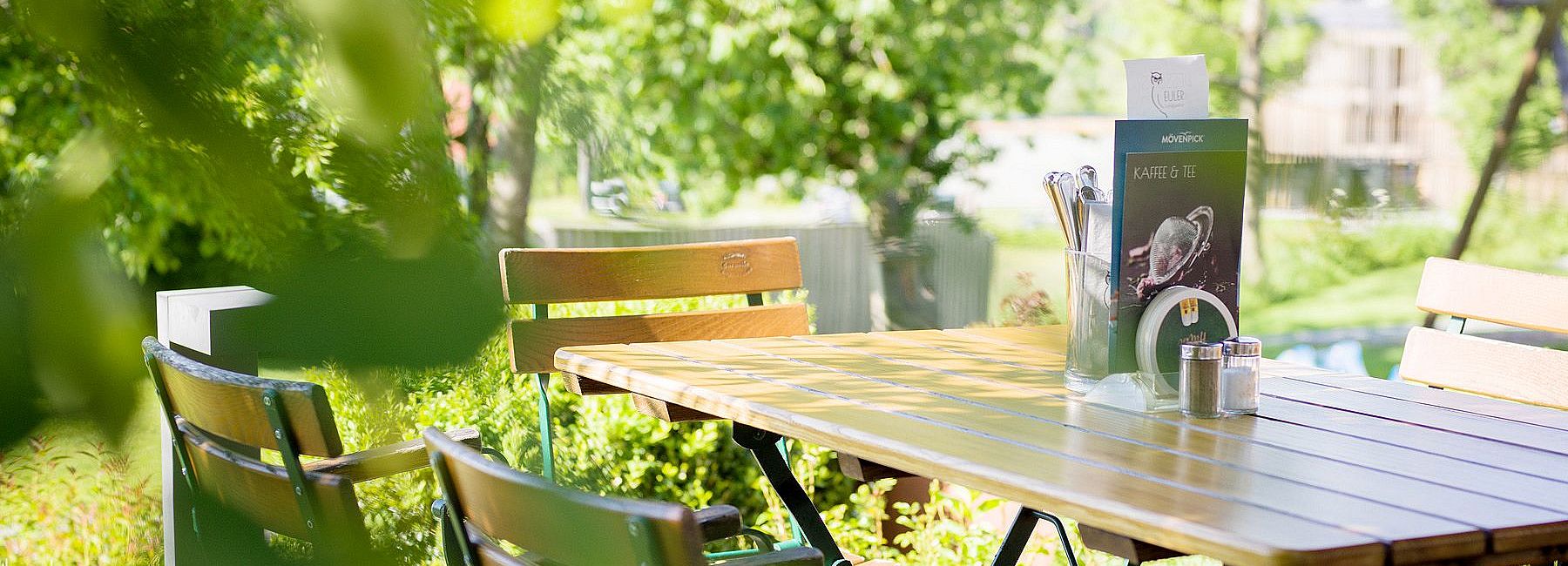 Holztisch mit Holzstühlen im Biergarten des Euler Landgasthofs im Sommer