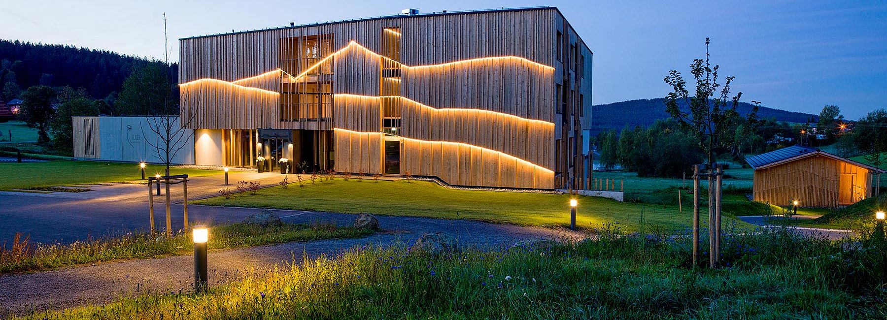 Das beleuchtete Naturhotel Euler Neuschönau in der Abenddämmerung im Sommer