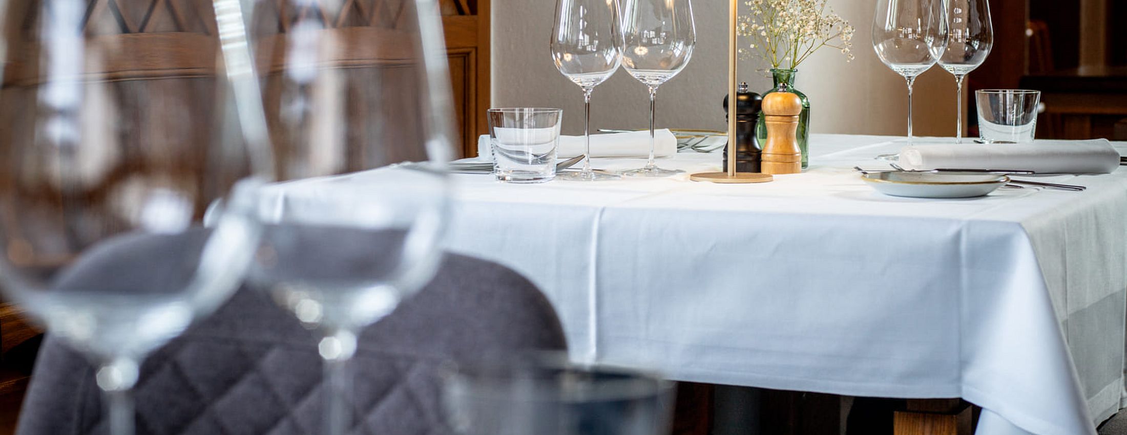 Stilvoll gedeckter Restauranttisch mit Weingläsern, Lampe und weißer Tischdecke