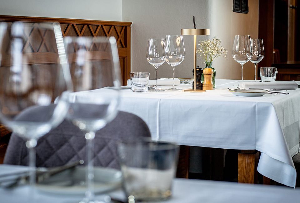 Stilvoll gedeckter Restauranttisch mit Weingläsern, Lampe und weißer Tischdecke