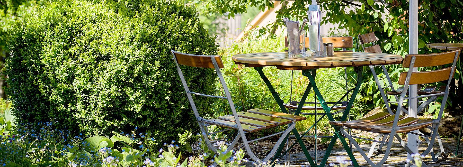 Kleiner Tisch mit Holzstühlen im Biergarten des Euler Landgasthofs im Sommer