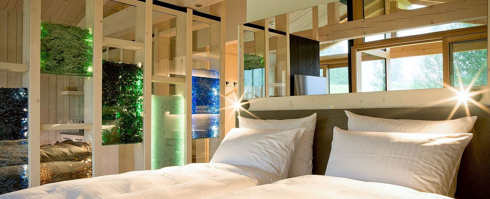 Doppelbett im Chalet mit hoher Decke und mit bunten Glasscherben gefüllte Wandelemente