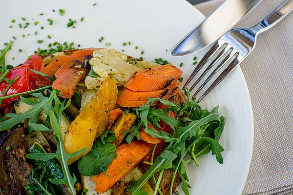 Buntes gebratenes Gemüse auf Brot mit Salat und frischen Kräutern