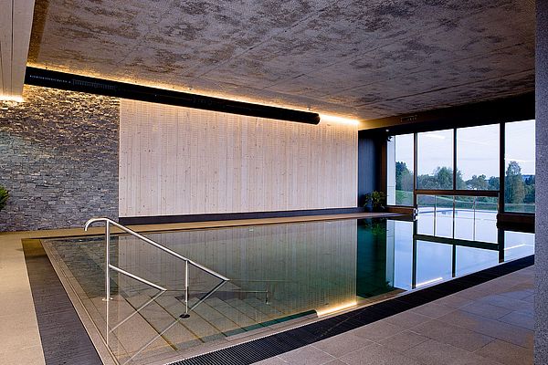 Pool mit Innen- und Außenbereich im Wellnessbereich mit Wanddekoration aus Holz