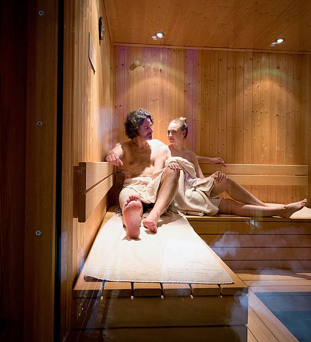 Paar entspannt gemeinsam in der Sauna auf Holzliegen