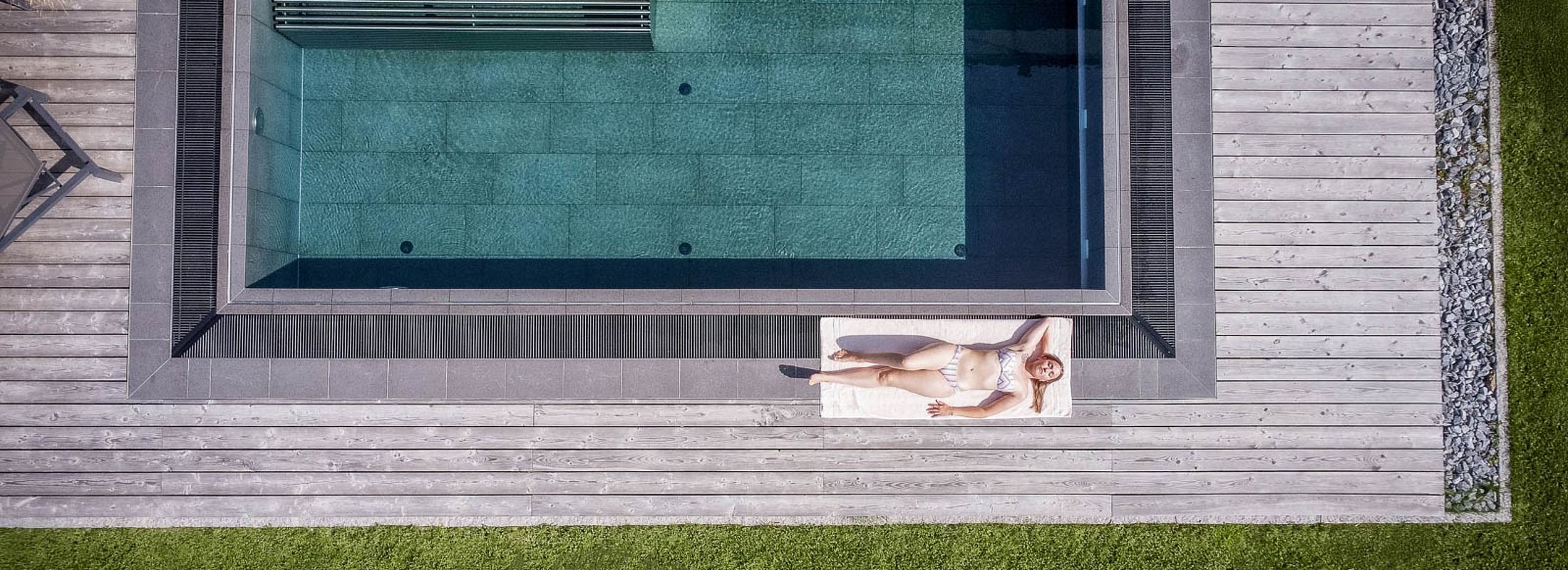 Drohnenaufnahme eines Infinitypools mit Holzdeck und Liegefläche am Naturhotel