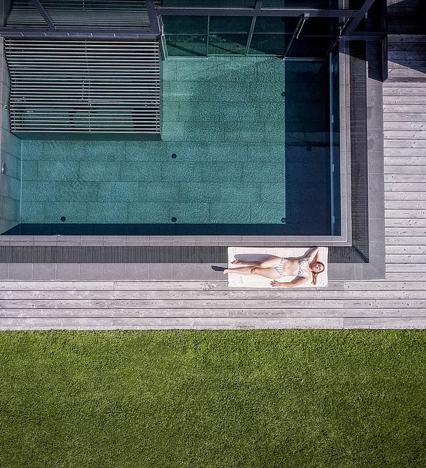 Drohnenaufnahme eines Infinitypools mit Holzdeck und Liegefläche am Naturhotel