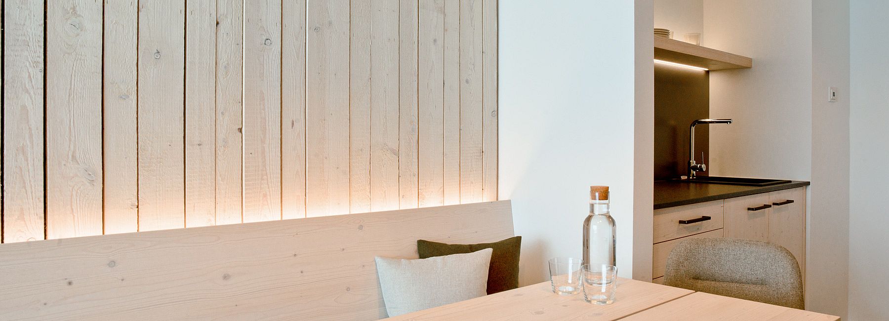 Küchenzeile und Sitzgruppe aus Holz in einer Suite mit holzvertäfelter Wand 