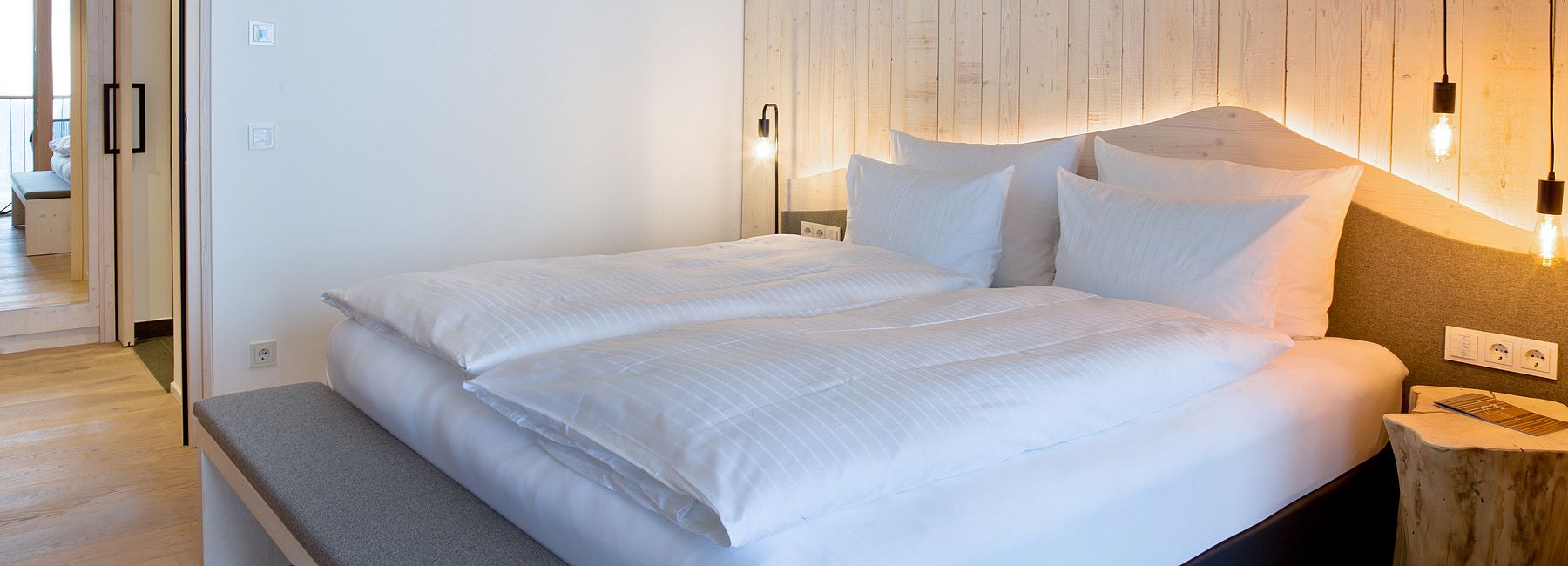 Doppelbett mit Holzkopfteil, indirekter Beleuchtung und eleganten Retro-Lampen