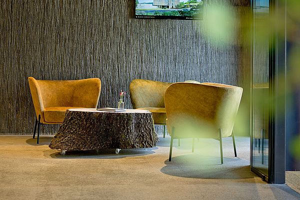 Loungebereich mit stilvollen und bequemen Sesseln und Baumstammtisch