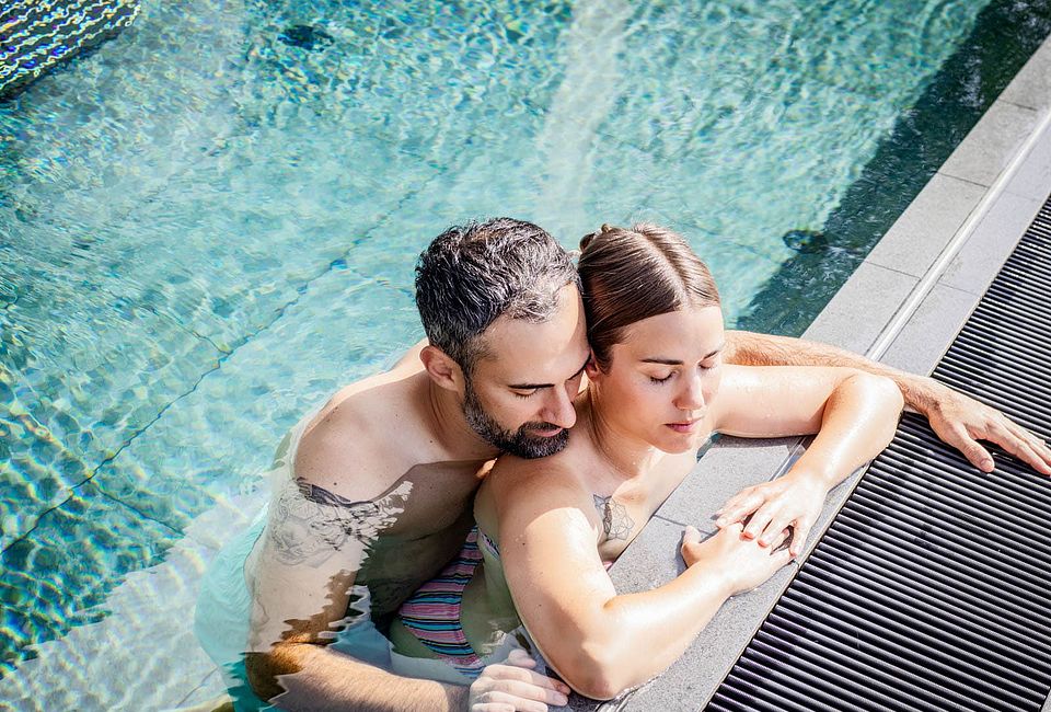 Couple relaxing together in the outdoor pool of the nature hotel