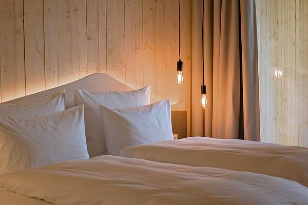 Doppelbett mit Kopfteil aus Holz und indirekter Beleuchtung mit modernen Deckenlampen