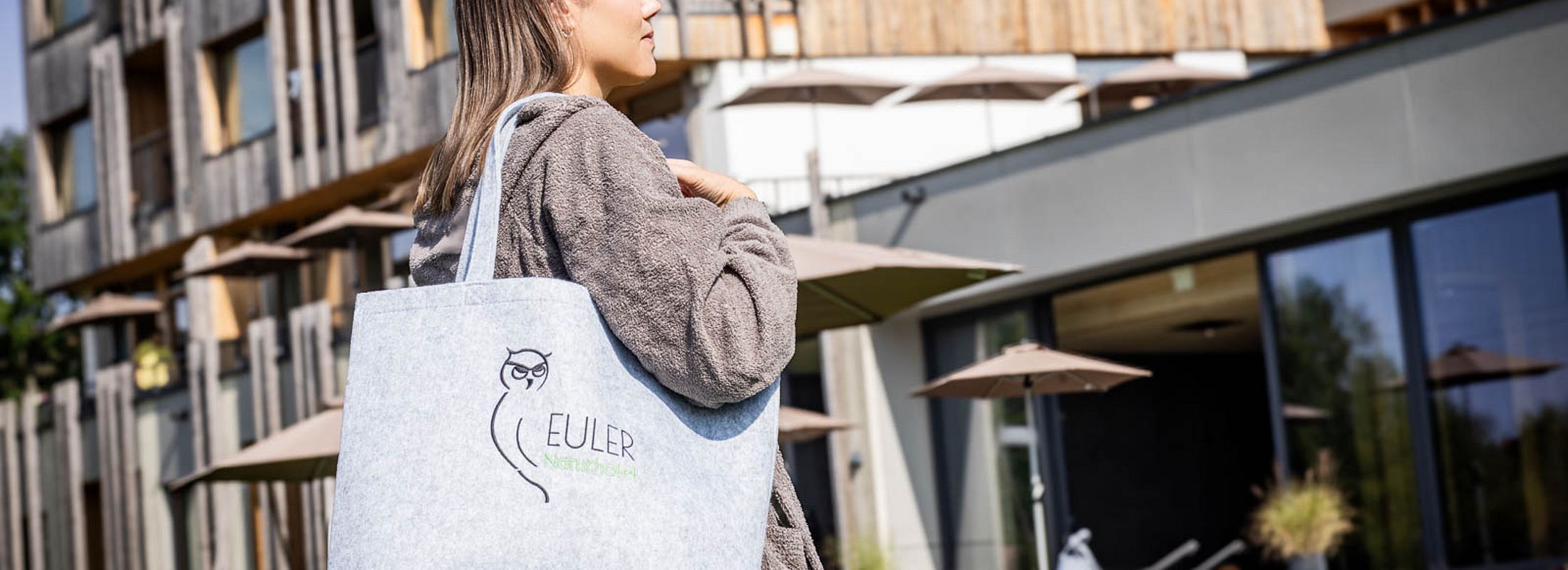 Hotelgast mit Euler Naturhotel Tasche auf der Liegewiese vor dem Hotelgebäude