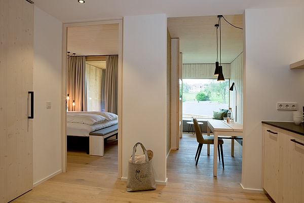 Modernes Zimmer mit Parkettboden, Holzmöbeln, Doppelbett und Wohnbereich mit Sitzecke