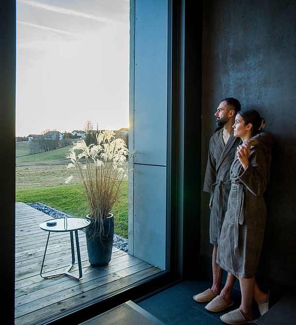 Paar im Wellnessbereich am Fenster bei Sonnenuntergang