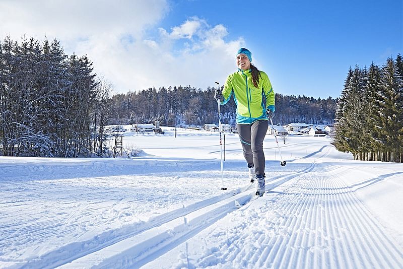 Frau beim Langlaufen auf perfekt gespurter Loipe in Winterlandschaft