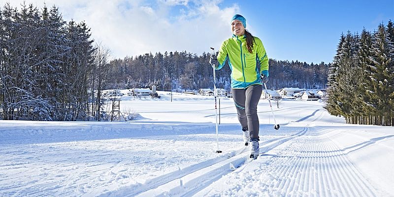 Frau beim Langlaufen auf perfekt gespurter Loipe in Winterlandschaft