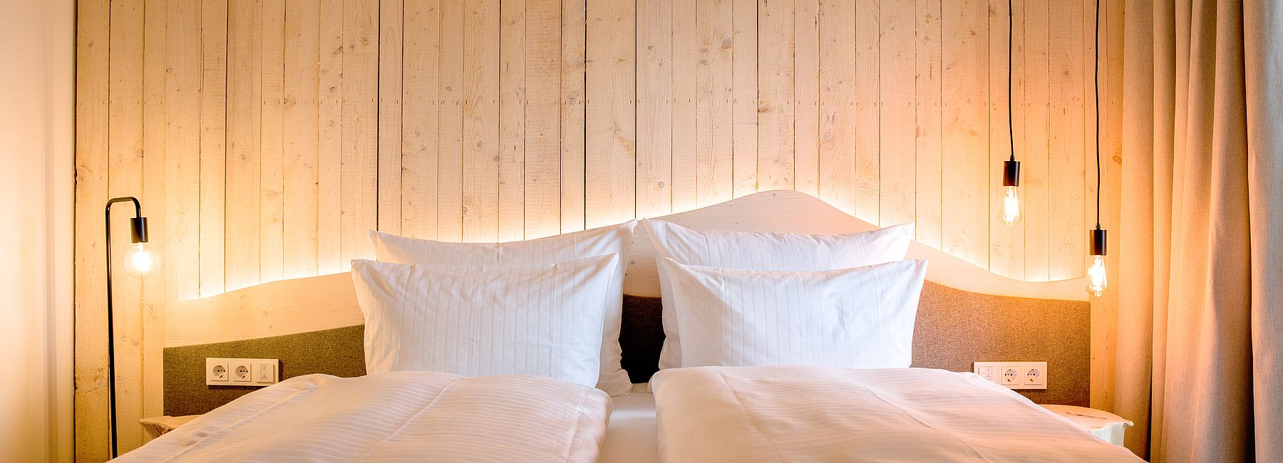 Doppelbett mit Kopfteil aus Holz und indirekter Beleuchtung mit modernen Retro-Lampen