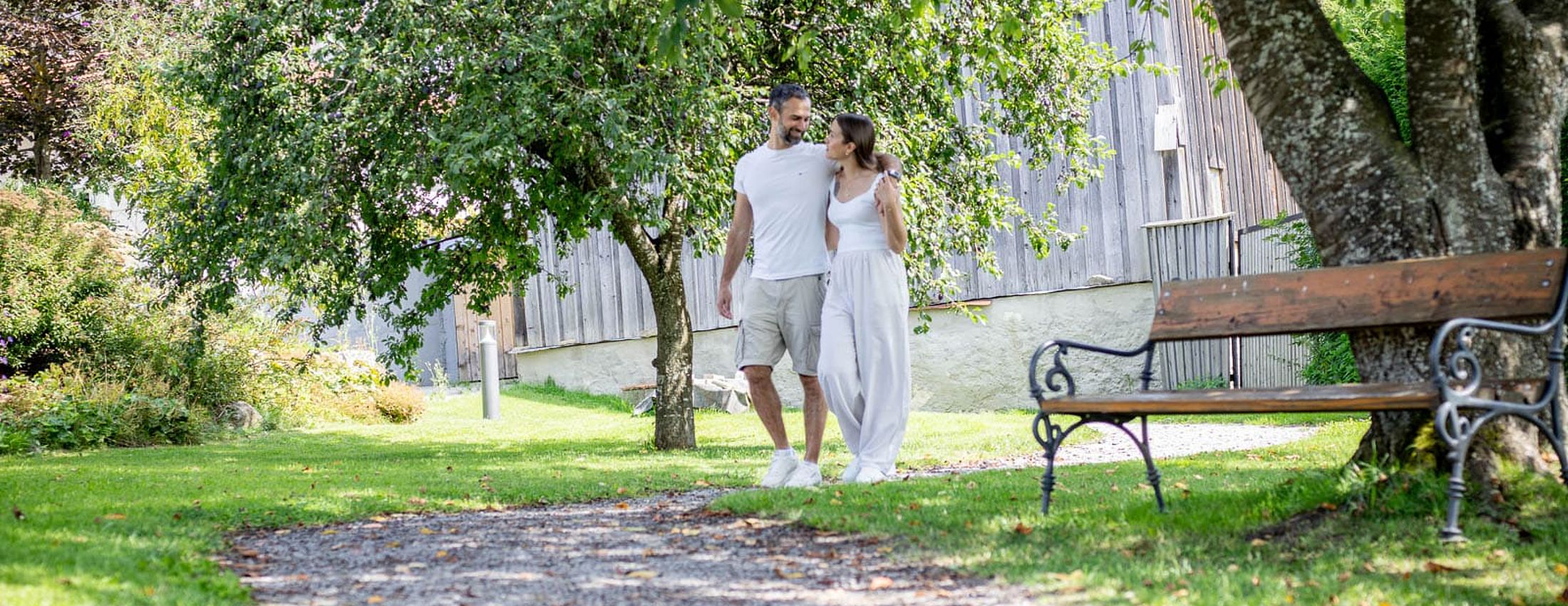 Couple walking through a green park area next to a wooden building